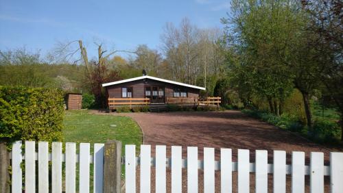 a house with a white fence in front of it at Chalet de vacances in Guisy