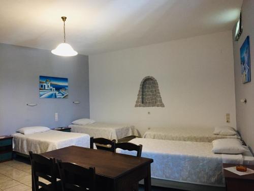 a room with two beds and a table and a table and chairs at Sofia Village in Mýkonos City