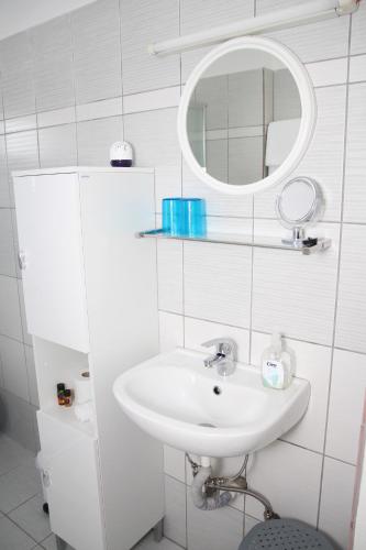 a white bathroom with a sink and a mirror at Olympias Studio "Pitsidia" in Pitsidia