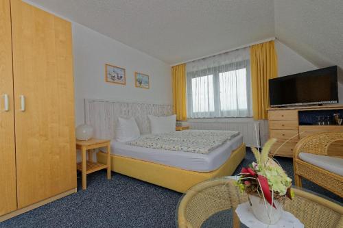a hotel room with a bed and a television at Pension Am Kirschberg in Bannewitz