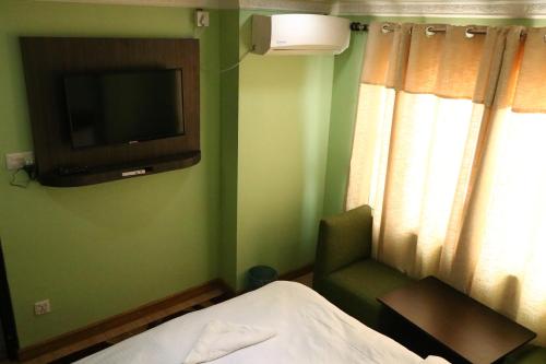 1 dormitorio con TV, 1 cama y 1 silla en Hotel Samrajya Pvt. Ltd., en Katmandú
