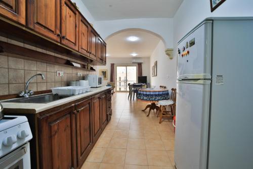 a kitchen with wooden cabinets and a white refrigerator at Island Break Residence in Marsalforn