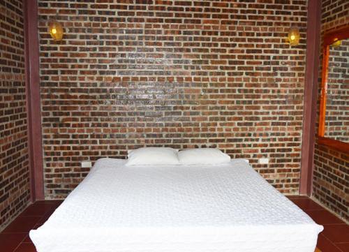a bedroom with a brick wall with a white bed at Van Long Family Homestay in Ninh Binh