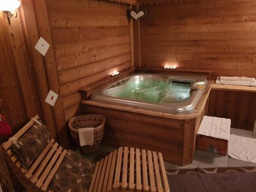 bañera de hidromasaje en una habitación de madera con banco en Hotel Rendez-Vous - Aymavilles, en Aymavilles