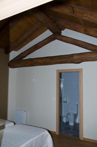 a bedroom with a bed and a bathroom with a toilet at PENSION SERRANO in Sarria
