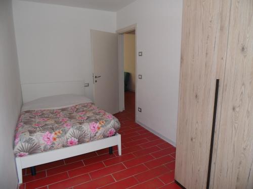 a bedroom with a bed and a red tile floor at Mini Viale Farra in Feltre