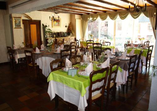 une salle à manger avec des tables, des chaises et un tissu de table vert dans l'établissement Hotel Restaurant des Deux Vallées, à Entraygues-sur-Truyère