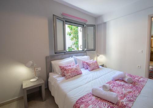 um quarto com uma grande cama branca com almofadas cor-de-rosa em Ithaka Zante City Villa em Zakynthos