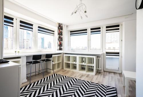 Elegant Apartment Panoramic في وارسو: غرفة معيشة بها نوافذ وسجادة بيضاء وسوداء