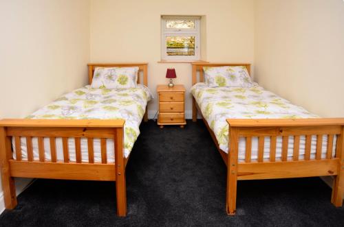 a bedroom with two beds and a night stand at Cottage 194 - Leenane in Leenaun