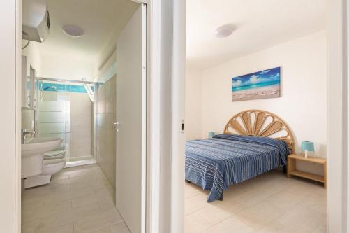a bedroom with a bed and a bathroom with a sink at Residence Kalura by BarbarHouse in Porto Cesareo