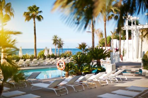 a pool with chairs and the ocean in the background at Puente Romano Marbella in Marbella