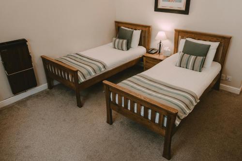 two beds in a room with two chairs and a lamp at Nant Ddu Lodge Hotel & Spa in Merthyr Tydfil