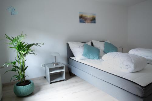 a bed with white and blue pillows and a plant at Bungalow near by Playmobil and fair Nuremberg in Zirndorf