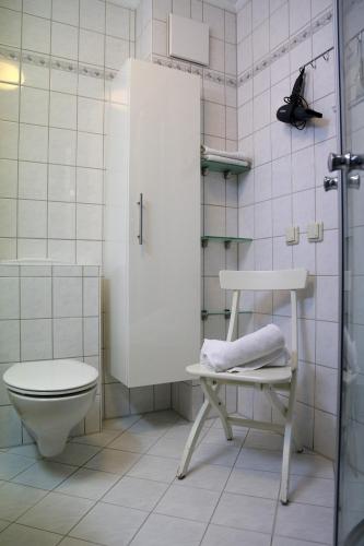 a bathroom with a toilet and a chair in it at K & R Appartements Binz in Binz