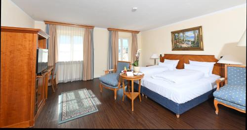 アシャウ・イム・キームガウにあるレジデンツ ハインツ ウィンクラーのベッド、テーブル、椅子が備わるホテルルームです。