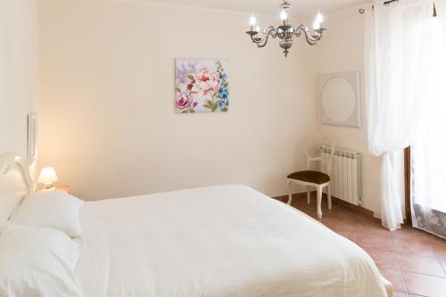 a white bedroom with a white bed and a chandelier at Venere in Borghetto