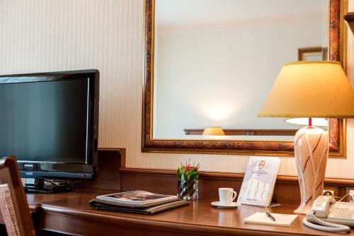 a hotel room with a desk with a television and a lamp at Crystal Palace Boutique Hotel in Sofia