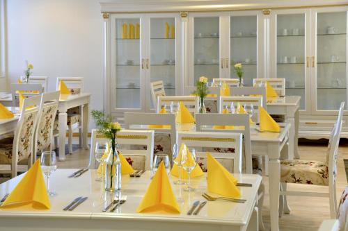 a dining room with white tables and yellow napkins at Hotel Golden Dome Iisalmi in Iisalmi