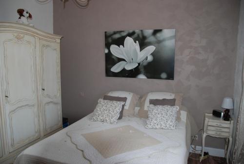 een slaapkamer met een bed en een bloemenfoto aan de muur bij La Villa Poupée in Grambois
