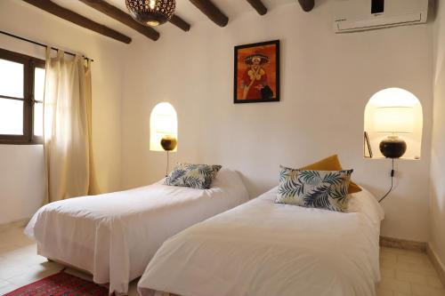 two beds in a room with white walls at Le Petit Hôtel du Flouka in Lalla Takerkoust