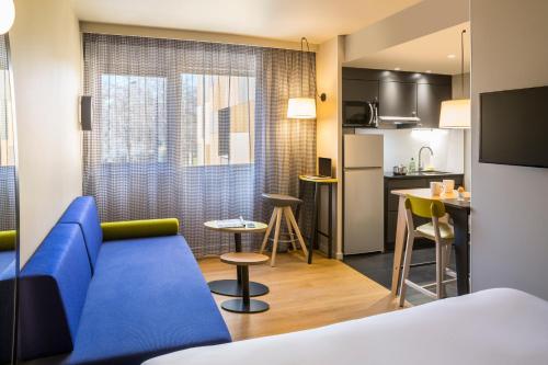 Habitación de hotel con sofá azul y cocina en Aparthotel Adagio access Montpellier Centre en Montpellier