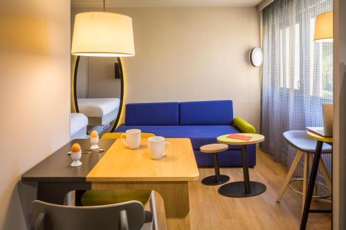 a living room with a blue couch and a table at Aparthotel Adagio access Montpellier Centre in Montpellier