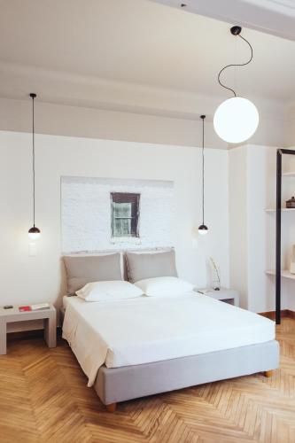 a bedroom with a white bed and a wooden floor at we saw athens in Athens