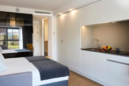 a bedroom with a white bed and a kitchen at Sercotel Valencia Alameda 41 in Valencia