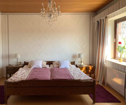 a bedroom with a bed with pink sheets and a chandelier at 29 Haster Straße in Bad Nenndorf