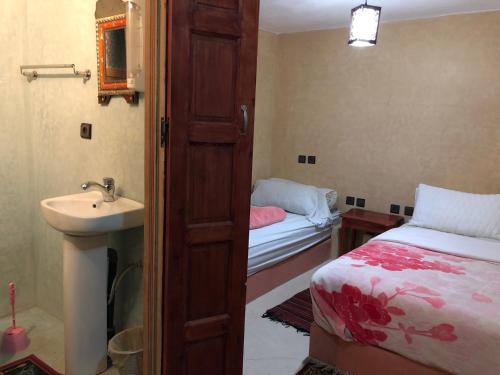 a bathroom with a bed and a sink next to a door at Auberge des lacs in Imilchil