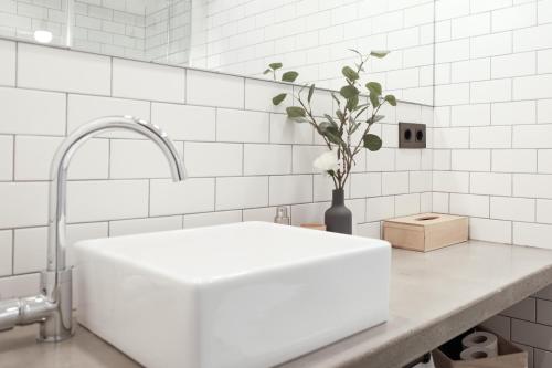 a white kitchen with a sink and a vase with flowers at Talo Urban Rooms in San Sebastián