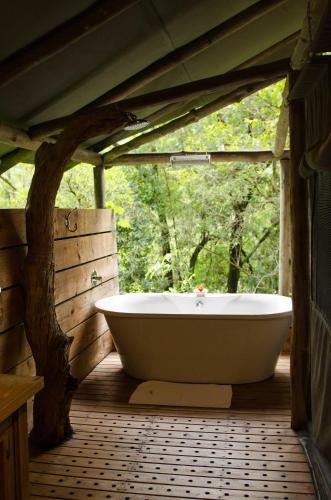 a bath tub sitting in a room with a window at Summerfields Rose Retreat and Spa in Hazyview