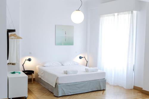 a white bedroom with a white bed and a window at we saw athens in Athens