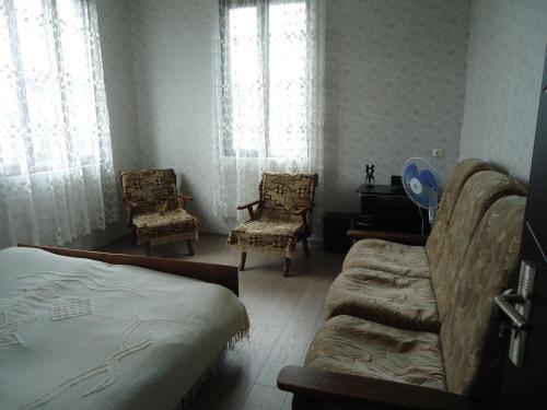 um quarto com 2 cadeiras, uma cama e janelas em Guesthouse Sesili em Batumi