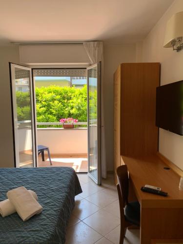 Cette chambre comprend un lit, un bureau et une télévision. dans l'établissement Hotel Mare Azzurro, à Terracine