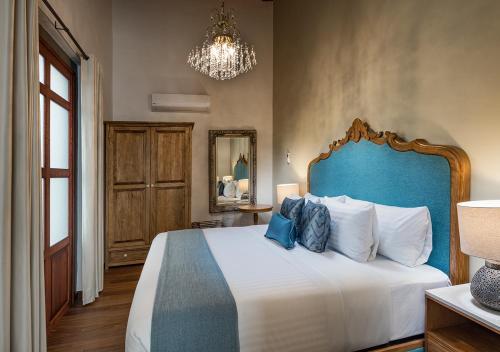 a bedroom with a large bed with a blue headboard at Hotel Casa Monarca in Puebla