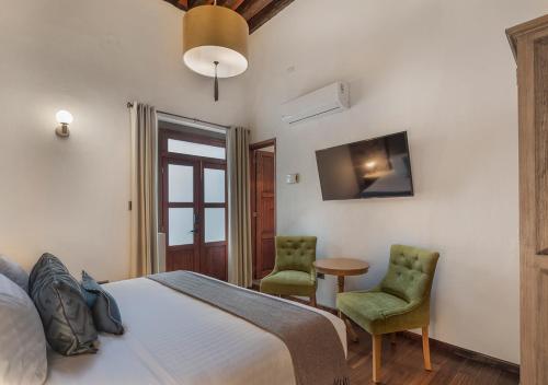 a bedroom with a bed and two chairs and a table at Hotel Casa Monarca in Puebla