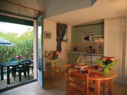 une cuisine avec des placards verts et une table avec une salle à manger dans l'établissement Lagrange Vacances Les Maisonnettes, à Sainte-Marie-Plage