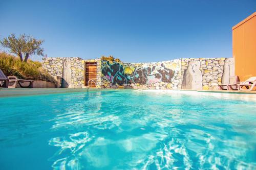 a swimming pool with a mural on a wall at Hôtel Ascosa Aventure in Ponte-Leccia