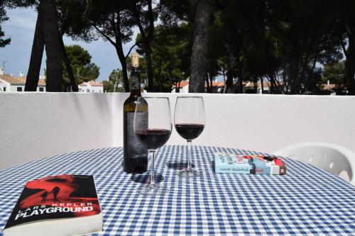 a bottle of wine and two glasses on a table at Apartamentos Las Brisas I & II in Cala'n Bosch