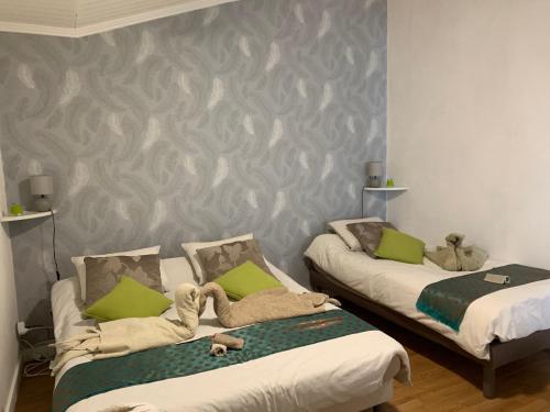 two beds in a room with green pillows at Chez Cathy in LʼHoumeau