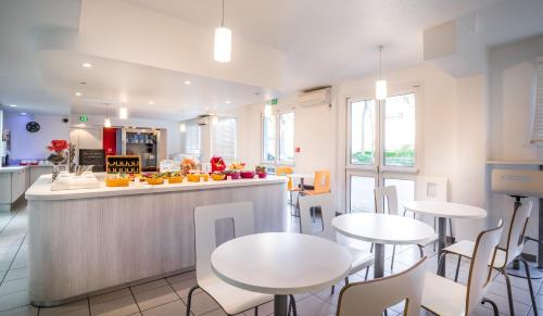 a kitchen and dining room with white tables and chairs at Première Classe Rosny Sous Bois in Rosny-sous-Bois