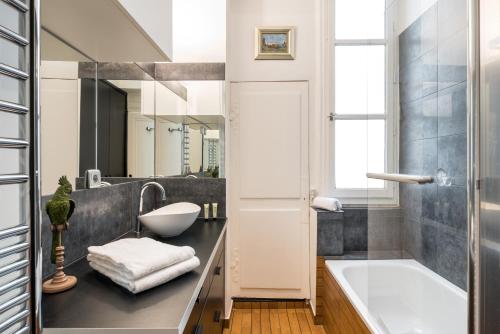 une salle de bain avec une baignoire et un lavabo et une baignoire dans l'établissement HONORÊ - Suite Victor Hugo, à Lyon