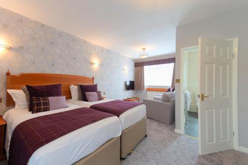 a hotel room with two beds and a bathroom at Appleby Manor Hotel & Garden Spa in Appleby