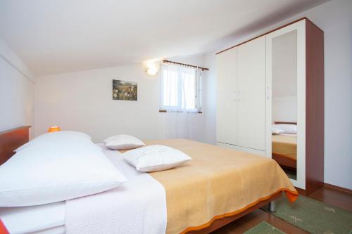 ein weißes Schlafzimmer mit einem Bett mit zwei Kissen in der Unterkunft Apartment Petra in Brodarica