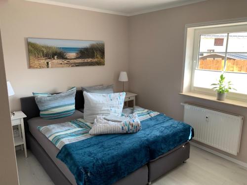 Schlafzimmer mit einem Bett mit blauer Bettwäsche und einem Fenster in der Unterkunft Op'n Dörp Apartments in Barsbek