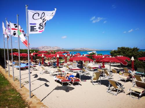 a beach with a lot of chairs and umbrellas at Club Esse Roccaruja in Stintino