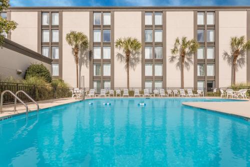 a large swimming pool in front of a building with palm trees at Wyndham Garden Summerville in Summerville
