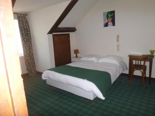 - une chambre avec un grand lit blanc et une couverture verte dans l'établissement Le Lurton, à Château-Renault